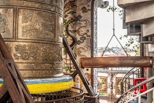 Inside an Asian sanctuary, monumental bronze bell, a symbol of spiritual resonance, is paired with substantial wooden beam, poised for rhythmic strikes. cultural and religious tradition
