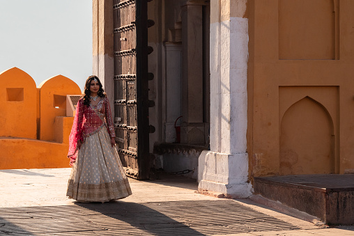 Jaipur, India 16 February 2024 Indian bride posing for a photoshoot in traditional red and gold wedding dress in Amer Fort