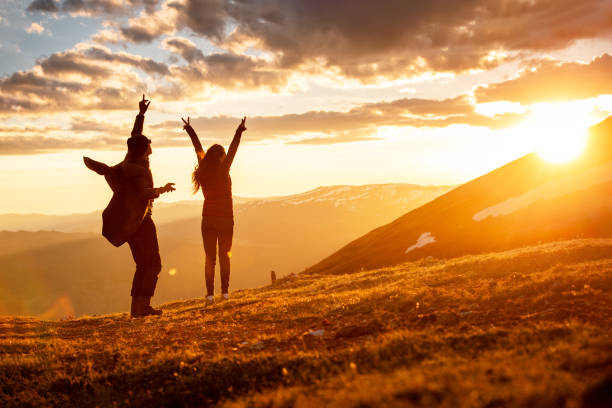 Two happy tourists are having fun in sunset mountains