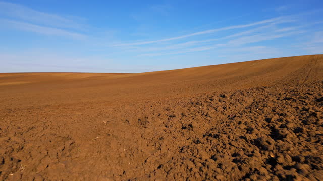 AERIAL Drone Shot of Freshly Plowed Soil in Agriculture Field in Countryside Under blue Sky
