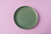 Empty green plate on pink background, top view, copy space.