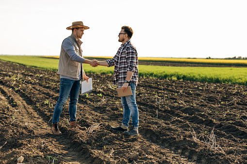 Two men shake hands on the field. Buying property.