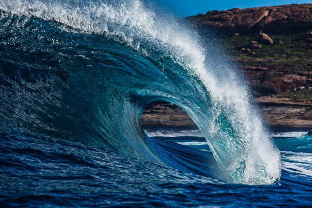 Large blue wave with perfect curl breaking in the open ocean over a shallow reef bombora. Photographed off the south west coast of Australia.