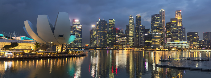 Singapore - December 28th, 2023: Marina Bay Modern Illuminated Cityscape at Night. Lights reflecting in the Marina Bay Pond from Singapore River. ArtScience Museum on the left. XPAN Panorama Format of downtown Illuminated Singapore City, Singapore, Southeast Asia.