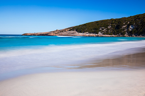 Coastal scene slow shutter captured smooth aqua marine blue ocean waves on the beach. Western Australia.