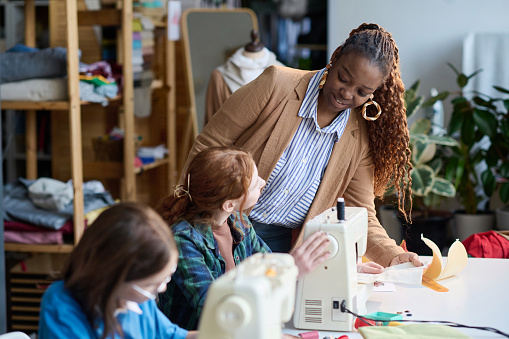 Portrait of Black adult woman talking to girl during atelier workshop class, copy space