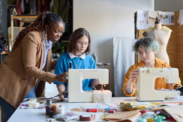 donna nera che aiuta le ragazze con disabilità in atelier - sewing women tailor teenage girls foto e immagini stock