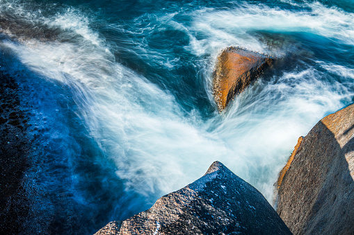 Slow shutter coastal scene with waves washing gently around rocks. Western Australia.
