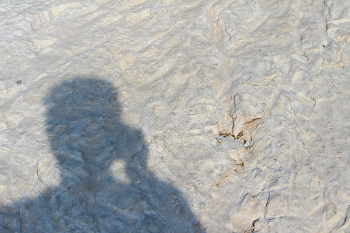 Shadow of the photographer on the white limestone surface of a rock. Marseille, Les Goudes, France.