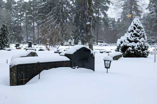 grave stones at cemetery covered in snow during winter