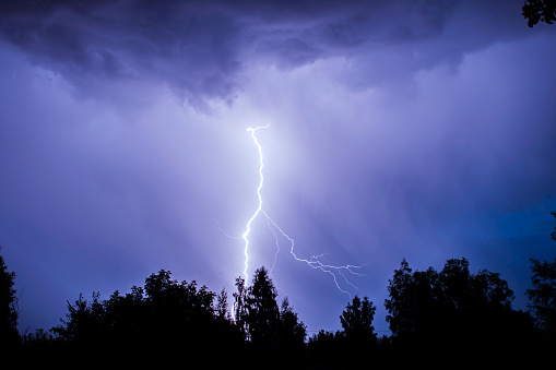 dramatic lightning thundertbolt bolt strike in daylight rural surrounding bad weather dark sky