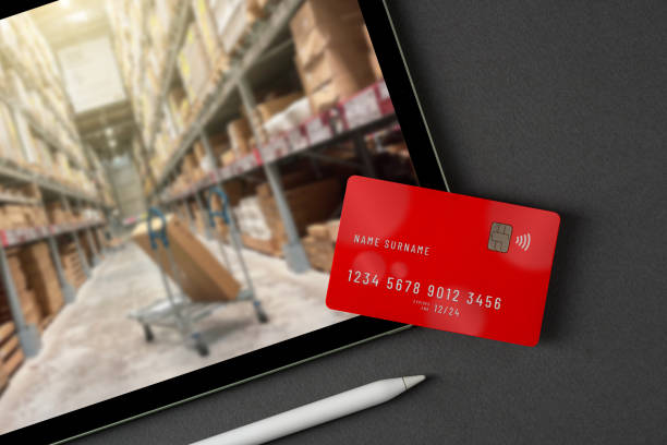 istock Red credit card on tablet with blurred market store on screen 2024646864