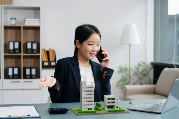 istock Young real estate agent worker working with laptop and tablet at table in office and small house beside it. 2024650075