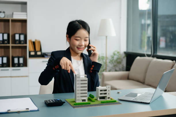 istock Young real estate agent worker working with laptop and tablet at table in office and small house beside it. 2024650092