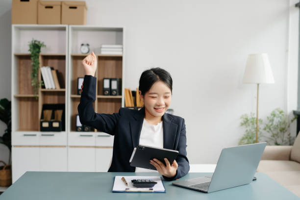 istock Young beautiful woman typing on tablet and laptop while sitting at the working white table 2024650610