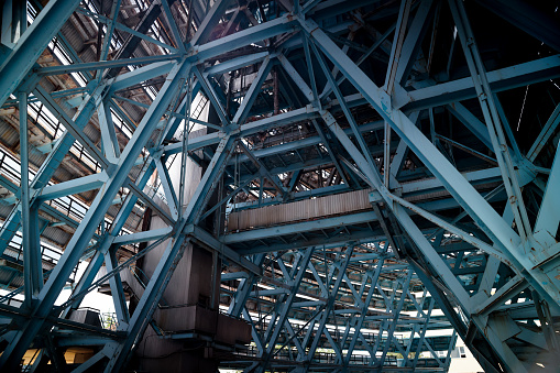 A very tall abandoned metal structure is depicted in the photo, featuring a multitude of metal beams extending in various directions.