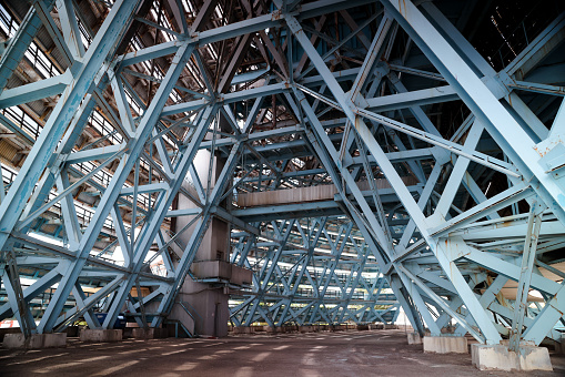 The photo shows the interior of an old abandoned building filled with an intricate network of metal beams. The beams support the structure and create a visually striking pattern throughout the space.