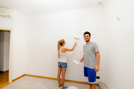 Young couple painting wall in a new house