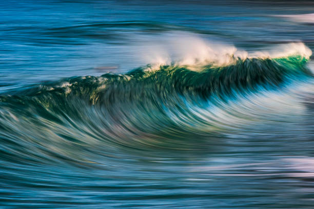 istock Slow shutter blur of smooth wave breaking on the beach with ambient soft golden light 2024677616