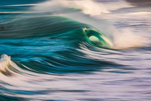 istock Slow shutter blur of smooth wave breaking on the beach with ambient soft golden light 2024678159