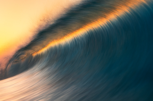 Motion blur of smooth wave forming in golden light. Photographed in Western Australia.