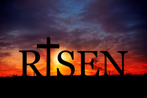 Word Risen over sunset sky. Easter holiday concept.