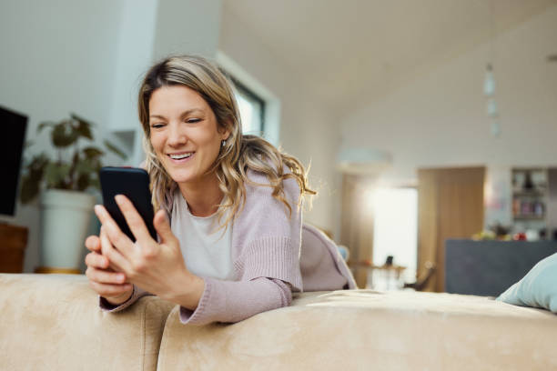 istock Happy woman text messaging on cell phone at home. 2024696395
