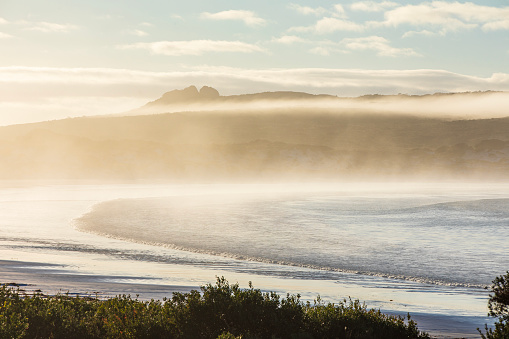 Sunrise over the beach with golden mist and fog at Lucky Bay in Esperance, Western Australia.