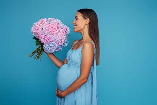 Emotional pregnant woman holding a bouquet of flowers