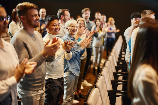 Happy people applauding on education event at convention center.