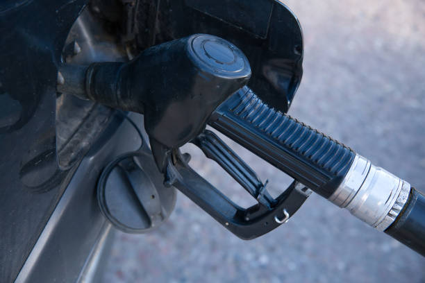 A gas station pistol is inserted into the car's gas tank.