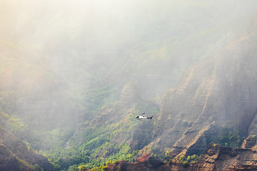 Helicopter flying through rain and mist over majestic mountains and valleys in Hawaii. Photographed in Waimea Canyon, Kauai, Hawaii.