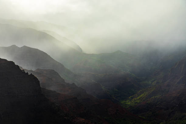 Rain and mist moving over majestic mountains and valleys in Hawaii. Photographed in Waimea Canyon, Kauai, Hawaii.