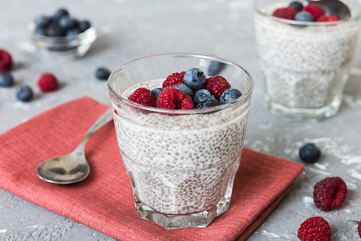 Healthy breakfast or morning with chia seeds vanilla pudding raspberry and blueberry berries on table background, vegetarian food, diet and health concept. Chia pudding with raspberry and blueberry.