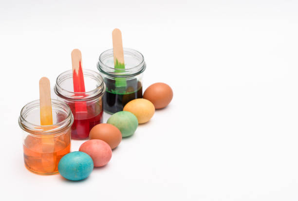 Painting Easter eggs with pastel colors, dyes in transparent jars next to Easter eggs