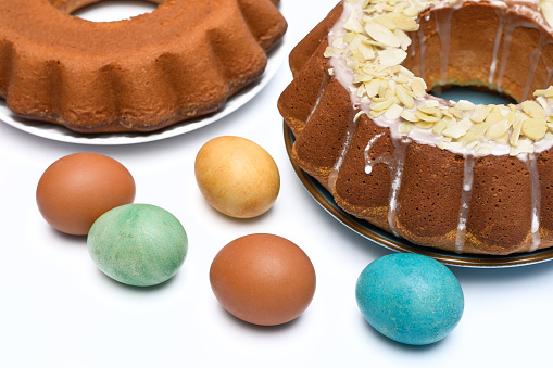 Easter babkas next to Easter eggs on a white background