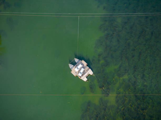 March 25, 2023 - Miravet, Spain: Aerial view of the small car ferry named Pas de Barca that carries 2 cars across the river Ebro outside Miravet village
