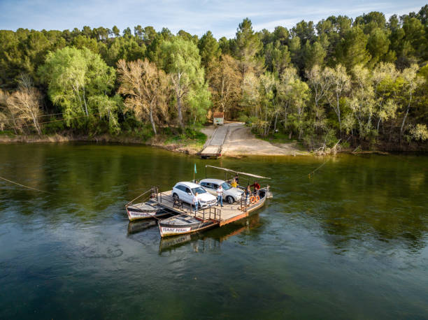 March 25, 2023 - Miravet, Spain: Aerial view of the small car ferry named Pas de Barca that carries 2 cars across the river Ebro outside Miravet village