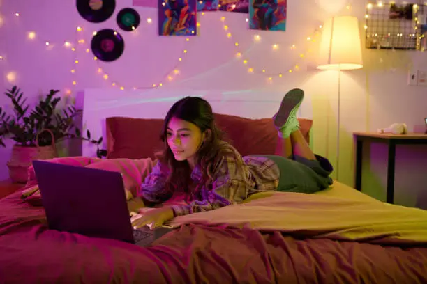 Girl resting on bed and browsing internet late at night