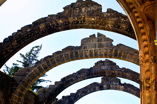 Close-up of ruins of ancient Santa Mariña de Dozo church, 12th century,  in Cambados, Pontevedra province, Rías Baixas, Galicia, Spain. Row of arched stone roof beams back lit, clear sky .