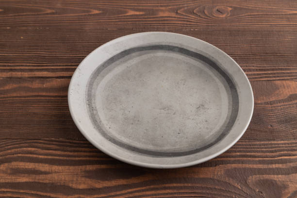 istock Empty gray ceramic plate on brown wooden. Side view, copy space 2024866850