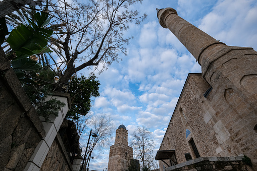 Antalya clock tower was built by Grand Vizier Küçük Sait Pasha in 1901. It was built for Abdülhamit. Tekeli Mehmet Pasha Mosque was built in the early 1600s. Two works together, wide angle shot from the bottom angle. The sky is cloudy.