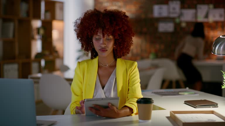 Black woman, tablet and laptop at night for research, project deadline or creative startup at office. African female person with afro working late with technology for online search, data or analysis