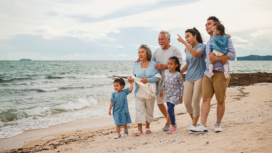 Cheerful Family and happy cute little daughter walk by the sea, enjoy the sea view and play together on vacation.