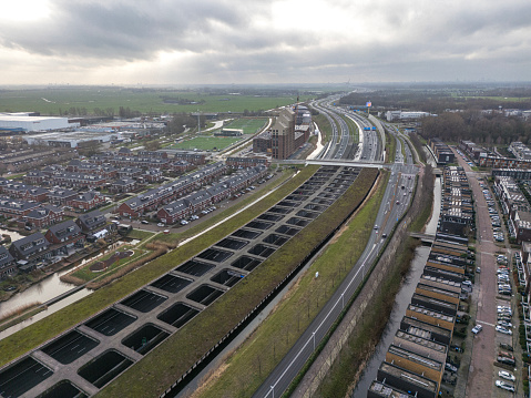Transport Infrastructure for cars and boats. Modern deepened motorway A4 close to Leiden, Netherlands. Surrounded bij a residential area. High angle view.