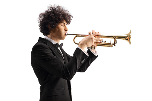 Profile shot of a young musician playing a trumpet isolated on white background
