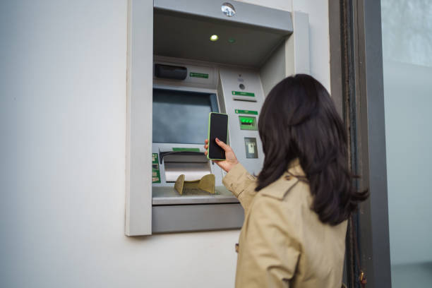 istock Asian Woman withdrawing money from ATM with mobile phone. 2024910708