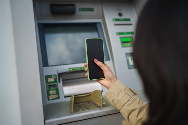 istock Asian Woman withdrawing money from ATM with mobile phone. 2024910712