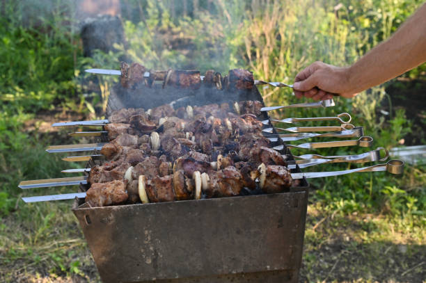 istock meat on skewers is cooked on the grill. a man turns over a skewer with meat 2024914998