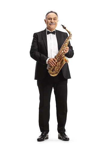 Full length portrait of a mature musician holding a sax and smiling isolated on white background